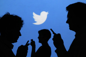 People holding mobile phones are silhouetted against a backdrop projected with the Twitter logo in this illustration picture taken in  Warsaw September 27, 2013. Twitter Inc, the eight-year-old online messaging service, gave potential investors their first glance at its financials on Thursday when it publicly filed its IPO documents, setting the stage for one of the most-anticipated debuts in over a year. Picture taken September 27.  REUTERS/Kacper Pempel (POLAND - Tags: BUSINESS TELECOMS LOGO)